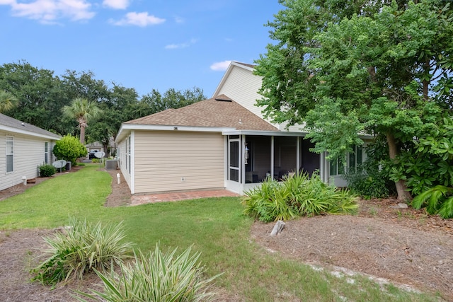 back of house with central AC unit, a lawn, a shingled roof, and a sunroom