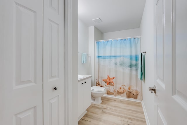 bathroom with vanity, a shower with shower curtain, wood finished floors, visible vents, and toilet