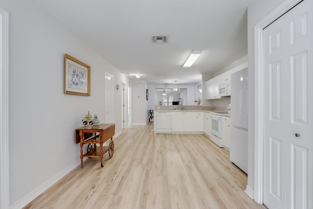 kitchen featuring visible vents, light countertops, light wood-style flooring, a peninsula, and white appliances