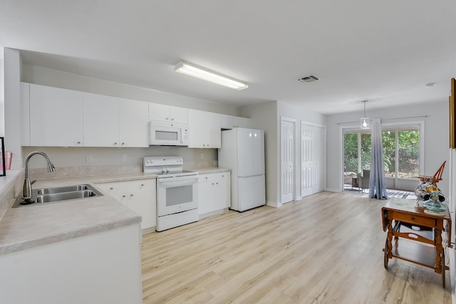 kitchen with white appliances, visible vents, light wood finished floors, a sink, and light countertops