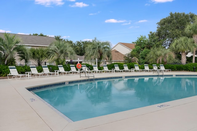 community pool with a patio area and fence