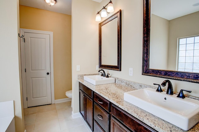 full bath with a sink, toilet, double vanity, and tile patterned flooring
