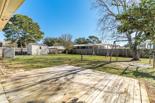 deck with a storage shed, an outbuilding, a fenced backyard, and a lawn