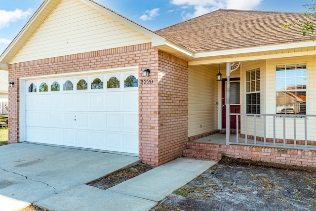 exterior space featuring driveway, a porch, an attached garage, a shingled roof, and brick siding