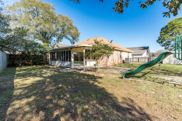 view of yard with a sunroom, a patio, a fenced backyard, and a playground