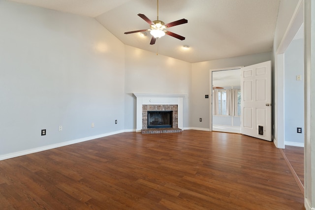 unfurnished living room featuring a fireplace with raised hearth, baseboards, lofted ceiling, wood finished floors, and a ceiling fan