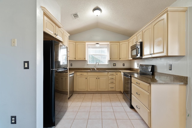 kitchen featuring dark countertops, light brown cabinets, light tile patterned flooring, black appliances, and a sink