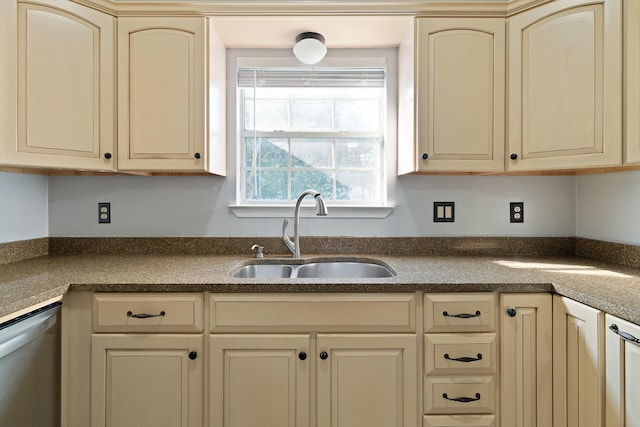 kitchen with a sink, dark countertops, and cream cabinetry