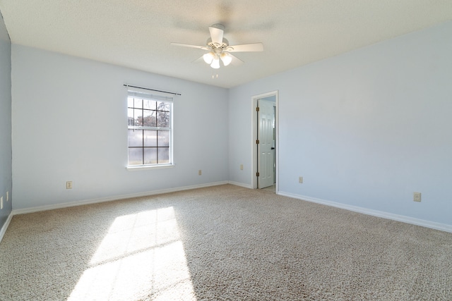 carpeted empty room with a textured ceiling, baseboards, and ceiling fan