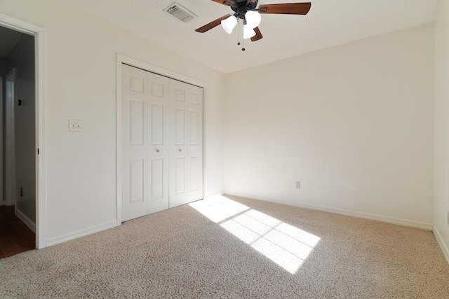 unfurnished bedroom featuring visible vents, ceiling fan, carpet flooring, a closet, and a textured ceiling