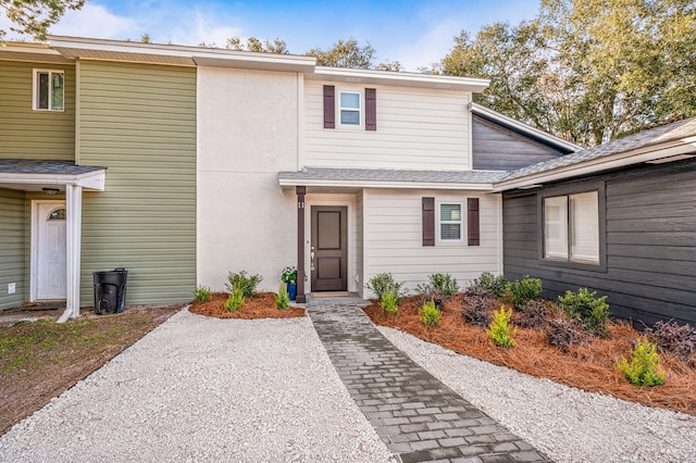 view of front of house with stucco siding and a shingled roof