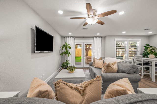 living area featuring wood finished floors, a ceiling fan, visible vents, and french doors