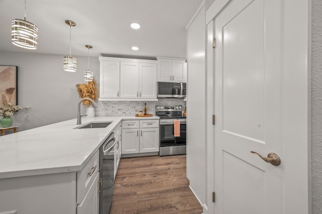 kitchen featuring dark wood-type flooring, a sink, tasteful backsplash, white cabinetry, and appliances with stainless steel finishes