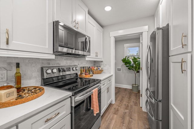 kitchen featuring backsplash, light countertops, appliances with stainless steel finishes, wood finished floors, and white cabinetry