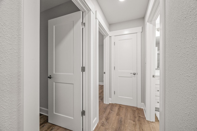 hall featuring a textured wall and wood finished floors