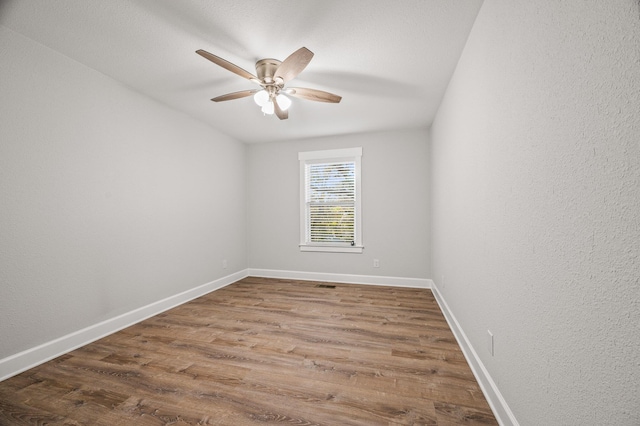 spare room featuring a ceiling fan, wood finished floors, and baseboards