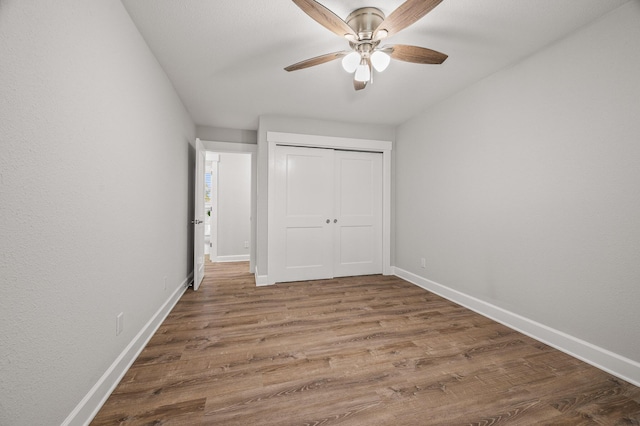 unfurnished bedroom with ceiling fan, a closet, baseboards, and wood finished floors