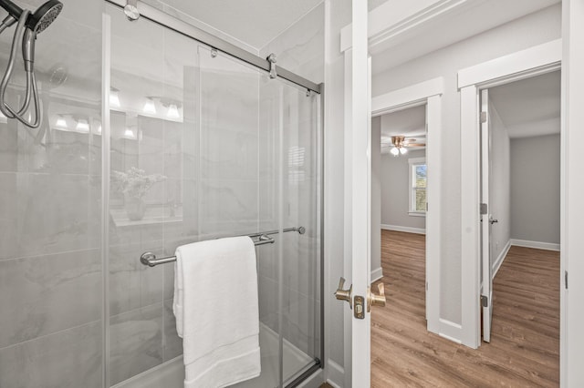 full bathroom with ceiling fan, wood finished floors, and a shower stall