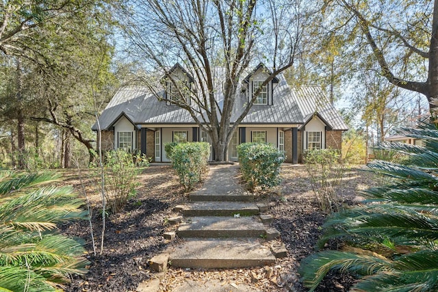 cape cod house featuring brick siding