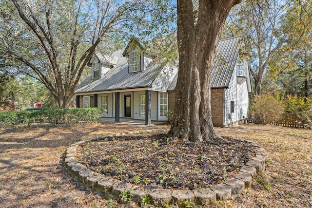 cape cod house featuring metal roof and a porch