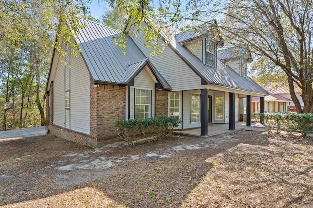 view of front of house with brick siding, covered porch, and metal roof