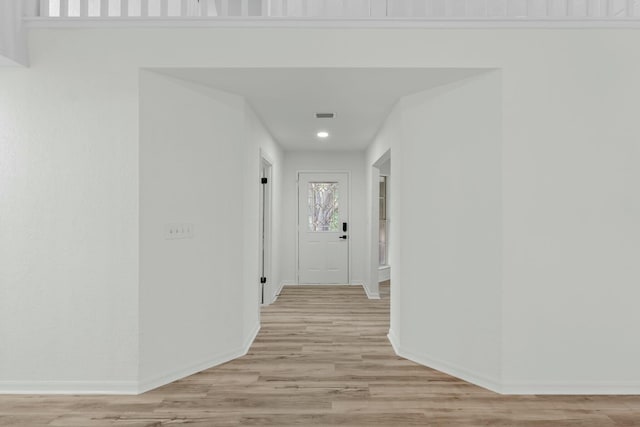 hallway with visible vents, light wood-style floors, and baseboards