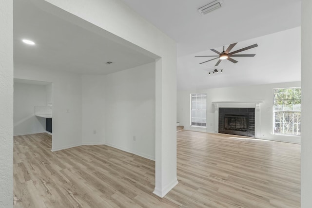 unfurnished living room with visible vents, a tile fireplace, light wood-type flooring, and a ceiling fan