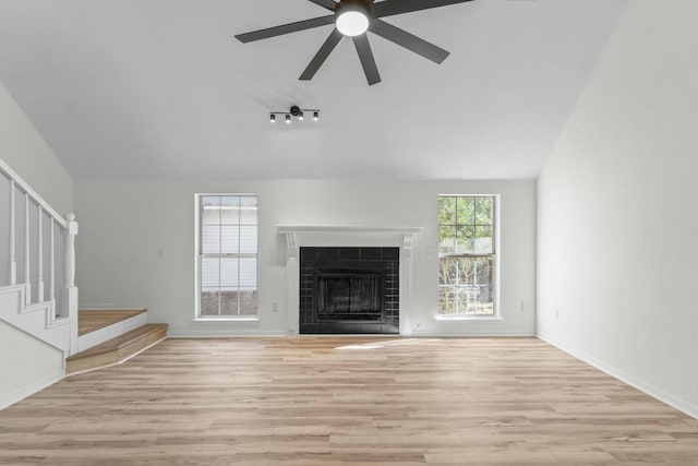 unfurnished living room featuring vaulted ceiling, stairway, wood finished floors, and ceiling fan