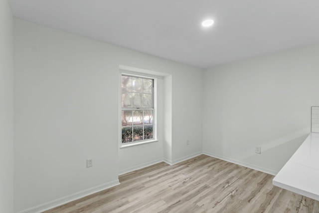 spare room featuring baseboards and light wood finished floors