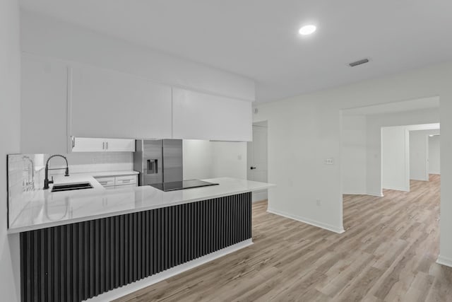 kitchen featuring visible vents, a sink, white cabinetry, stainless steel fridge with ice dispenser, and black electric cooktop