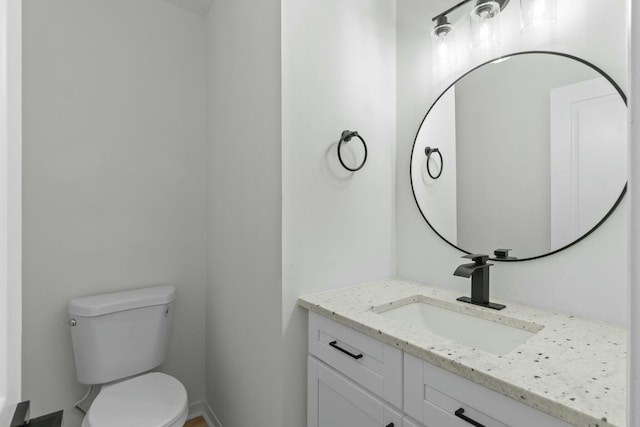 half bath featuring vanity and toilet