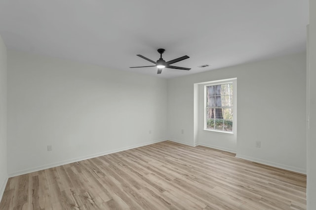 spare room with light wood-type flooring, baseboards, visible vents, and a ceiling fan