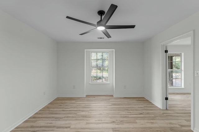 spare room featuring visible vents, a ceiling fan, light wood-style floors, and baseboards