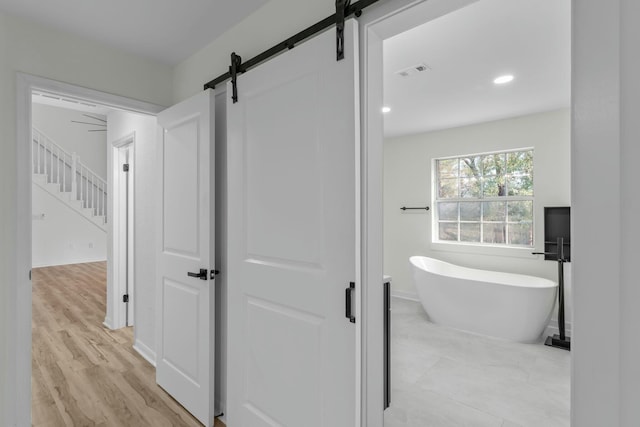 full bath with a freestanding tub, visible vents, wood finished floors, recessed lighting, and baseboards