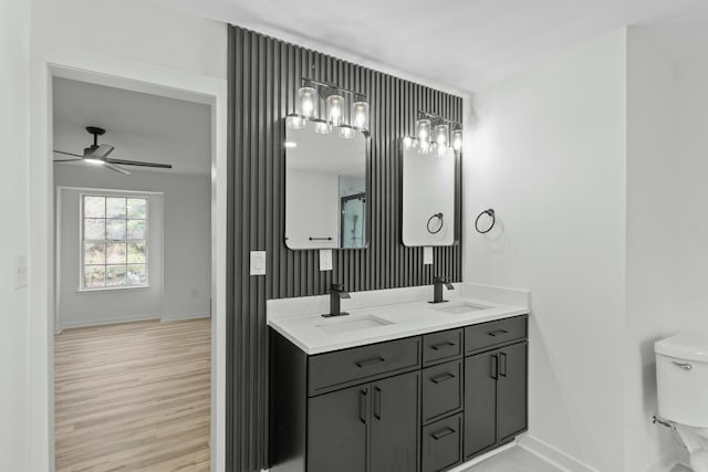 full bath featuring ceiling fan, toilet, wood finished floors, and a sink