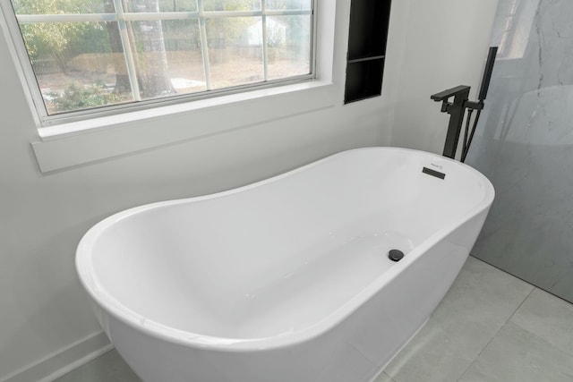 full bath featuring tile patterned floors, a freestanding tub, and plenty of natural light