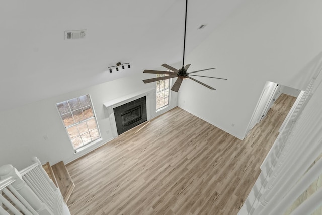 unfurnished living room with light wood-style flooring, a fireplace, a ceiling fan, and vaulted ceiling