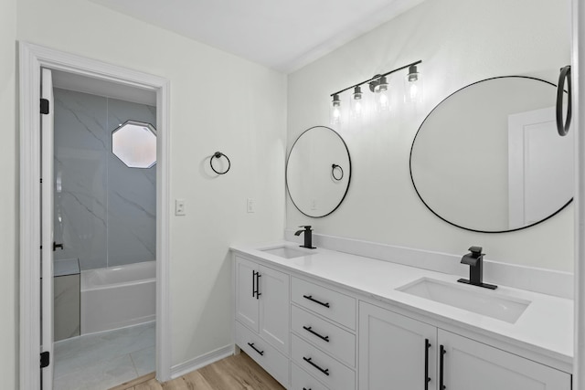 full bath with a sink, baseboards, wood finished floors, and double vanity