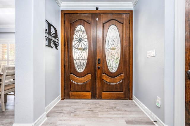 entryway with baseboards, light wood-style flooring, and crown molding