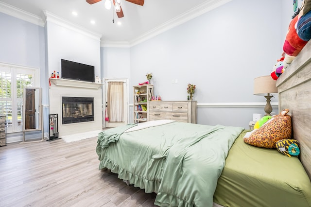 bedroom with a glass covered fireplace, recessed lighting, wood finished floors, and ornamental molding