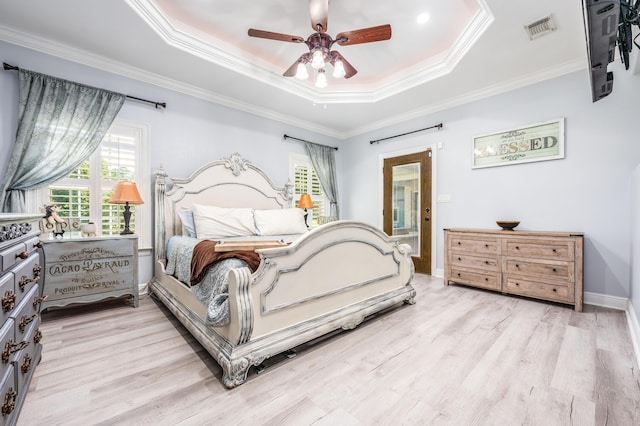 bedroom featuring a raised ceiling, crown molding, visible vents, and light wood-type flooring