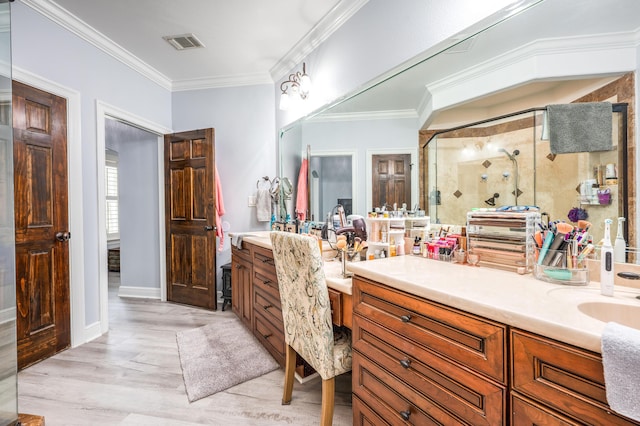 bathroom featuring wood finished floors, visible vents, double vanity, ornamental molding, and a shower stall