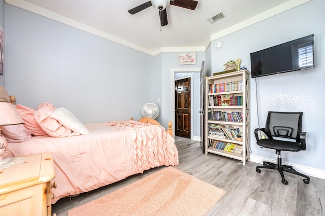 bedroom with wood finished floors, visible vents, baseboards, ceiling fan, and crown molding