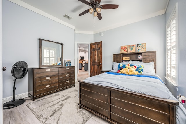 bedroom featuring wood finished floors, baseboards, visible vents, ceiling fan, and crown molding