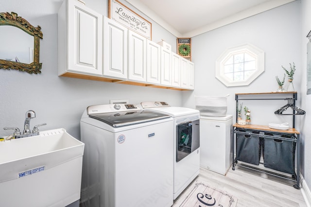 washroom featuring a sink, cabinet space, light wood-style floors, and washer and dryer