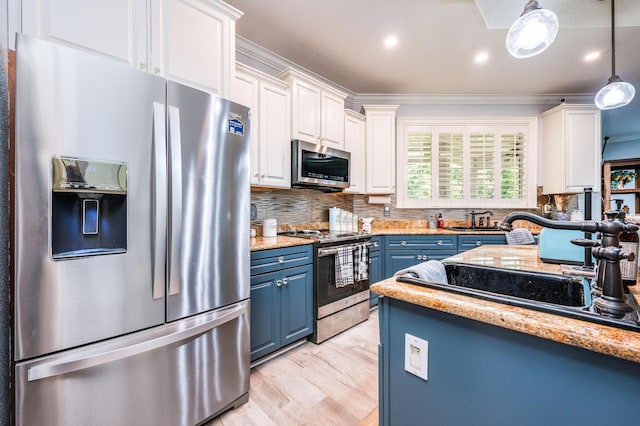 kitchen featuring blue cabinetry, appliances with stainless steel finishes, a sink, and white cabinetry