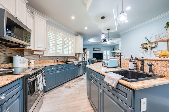 kitchen with blue cabinetry, crown molding, appliances with stainless steel finishes, white cabinets, and a sink