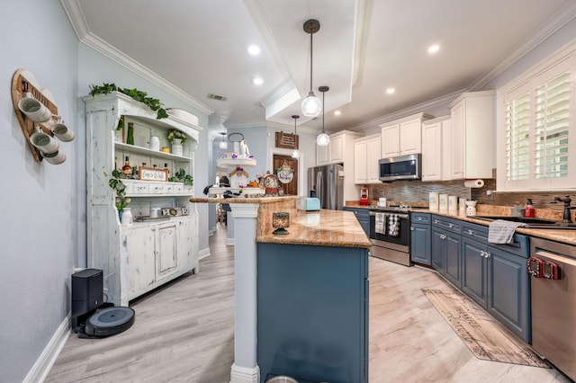 kitchen with visible vents, blue cabinetry, a kitchen island, appliances with stainless steel finishes, and a sink