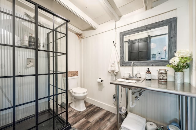 bathroom featuring wood finished floors, baseboards, beam ceiling, a sink, and toilet