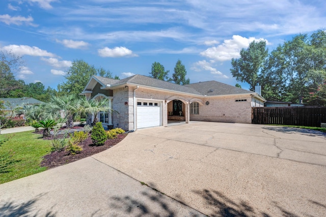 ranch-style house featuring concrete driveway, an attached garage, fence, and brick siding